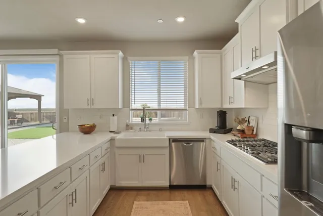 a kitchen with kitchen island white cabinets appliances and a sink