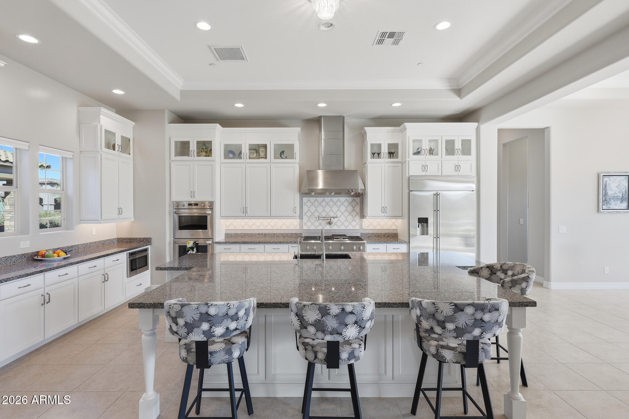 a kitchen with kitchen island granite countertop lots of white cabinets and stainless steel appliances