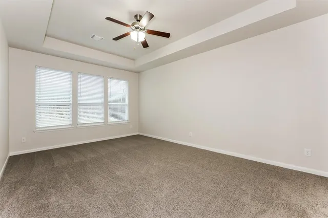 an empty room with windows and ceiling fan