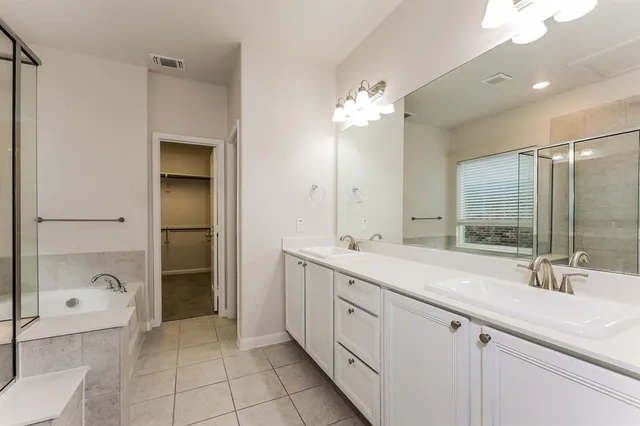 a spacious bathroom with a double vanity sink a mirror and a bathtub