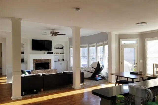 a kitchen with stainless steel appliances granite countertop a refrigerator a stove top oven a dining table and chairs with wooden floor