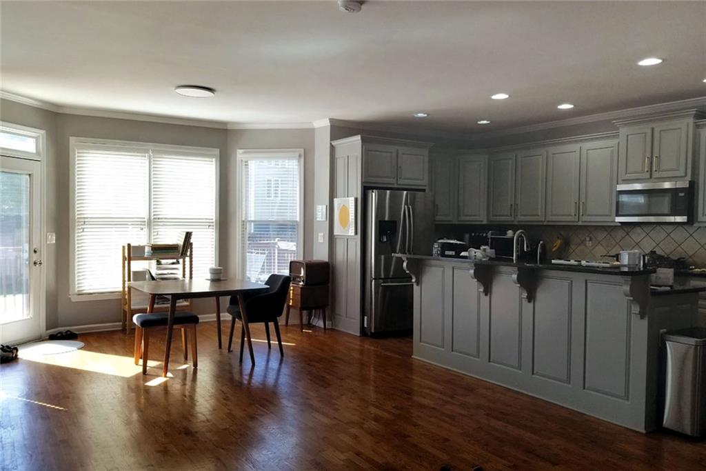 1799 Mapmaker Drive Northeast Dacula, GA 30019 - Photo 19 of 69 a kitchen with stainless steel appliances granite countertop a refrigerator a stove top oven a dining table and chairs with wooden floor
