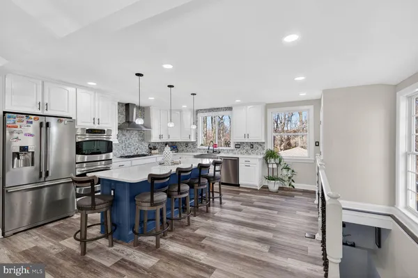 a kitchen with stainless steel appliances a dining table chairs refrigerator and cabinets