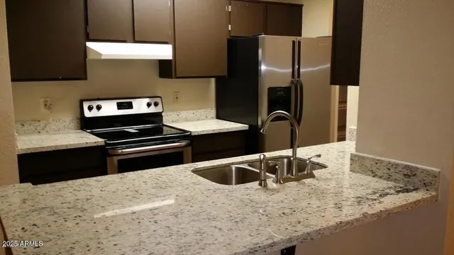 a kitchen with stainless steel appliances granite countertop a sink and a refrigerator
