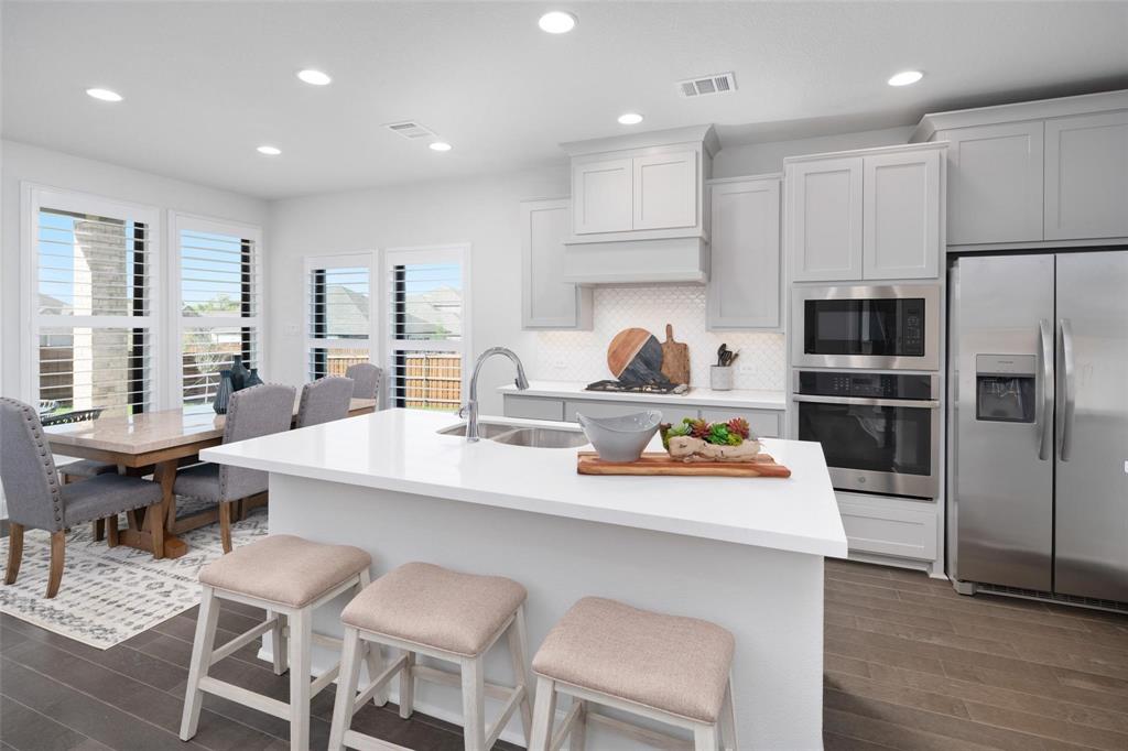 9600 Acorn Lane Little Elm, TX 75068 - Photo 7 of 34 a kitchen with a sink a stove a refrigerator and chairs
