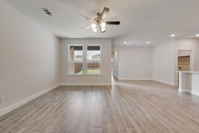 a view of an empty room with window and wooden floor