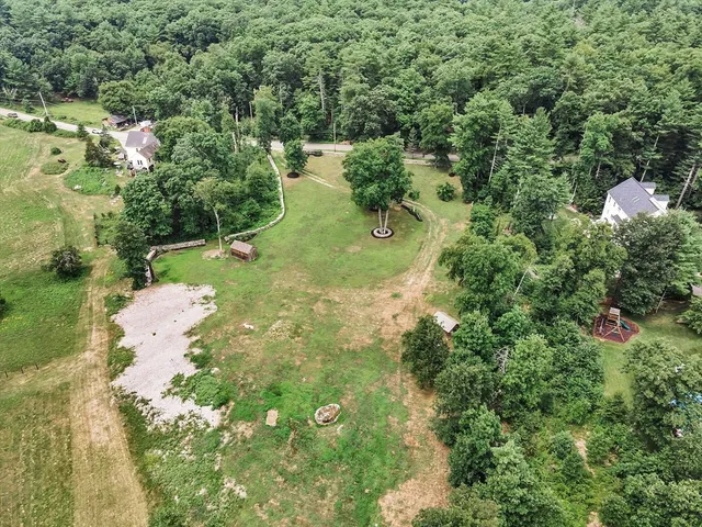 an aerial view of residential houses with outdoor space and trees