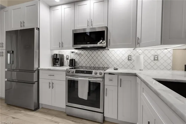 a kitchen with stainless steel appliances white cabinets and a refrigerator