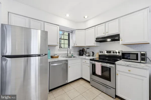 a kitchen with stainless steel appliances white cabinets and a refrigerator