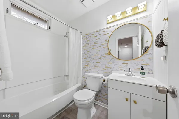 a bathroom with a toilet sink vanity tub and mirror