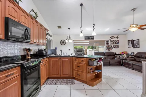 a open kitchen with stainless steel appliances granite countertop a stove a sink and a microwave