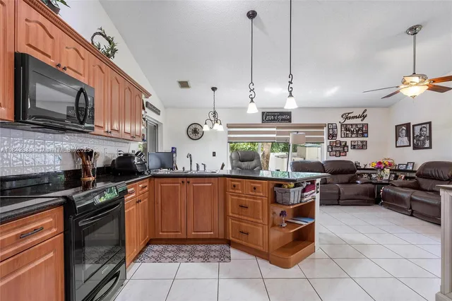 a open kitchen with stainless steel appliances granite countertop a stove a sink and a microwave