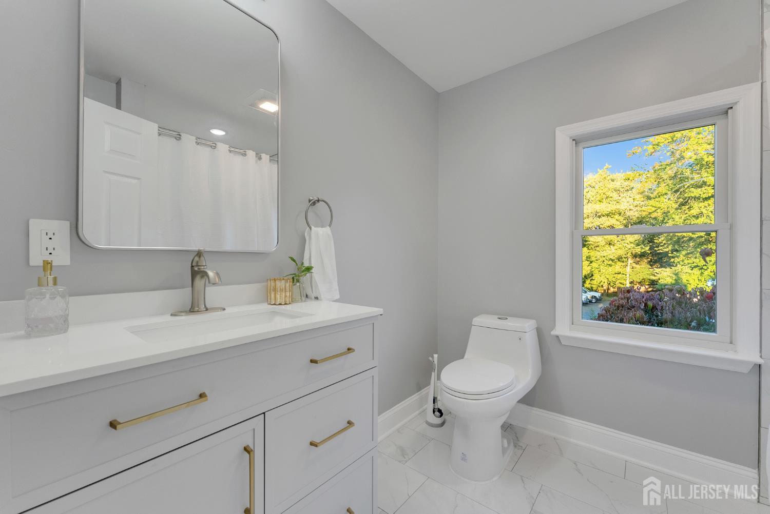 15 North Main Street, Unit B Pennington, NJ 08534 - Photo 12 of 16 a bathroom with a toilet a sink a mirror a window and vanity