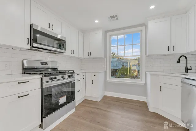 a kitchen with stainless steel appliances granite countertop a stove a sink and a microwave