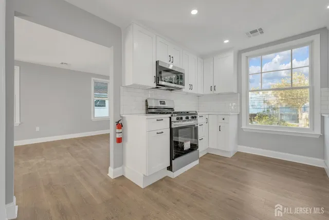 a kitchen with stainless steel appliances granite countertop a stove a sink and a microwave