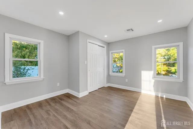 a view of an empty room with window and wooden floor