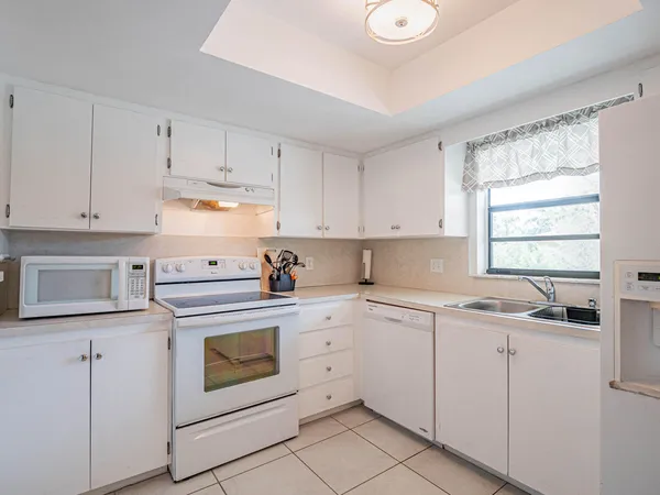 a kitchen with cabinets appliances a sink and a window