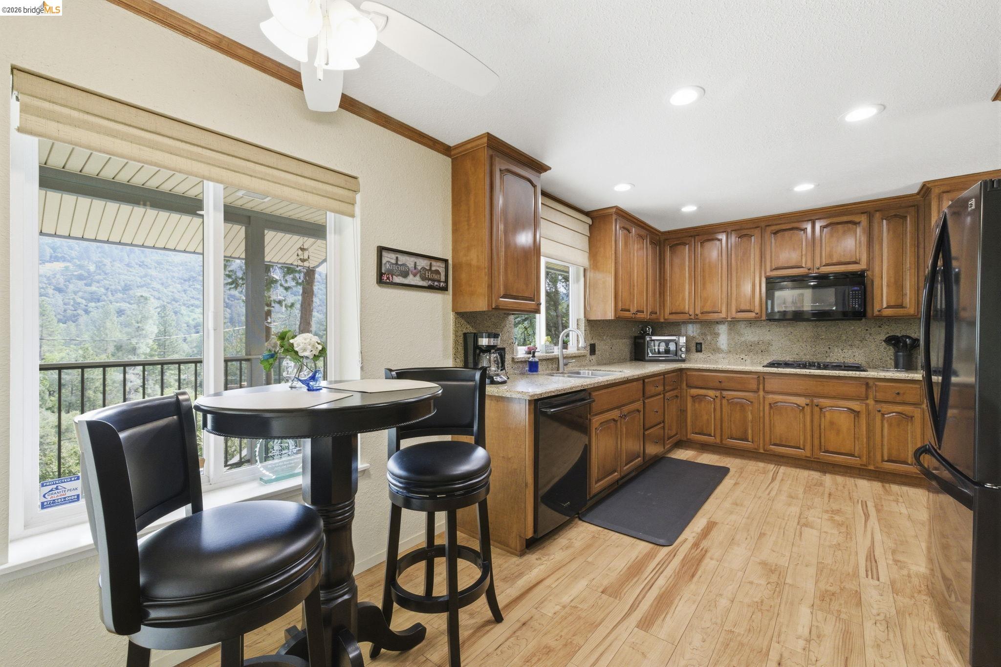 21955 Fallview Drive Sonora, CA 95370 - Photo 11 of 32 a kitchen with stainless steel appliances granite countertop a stove top oven a sink dishwasher a dining table and chairs with wooden floor
