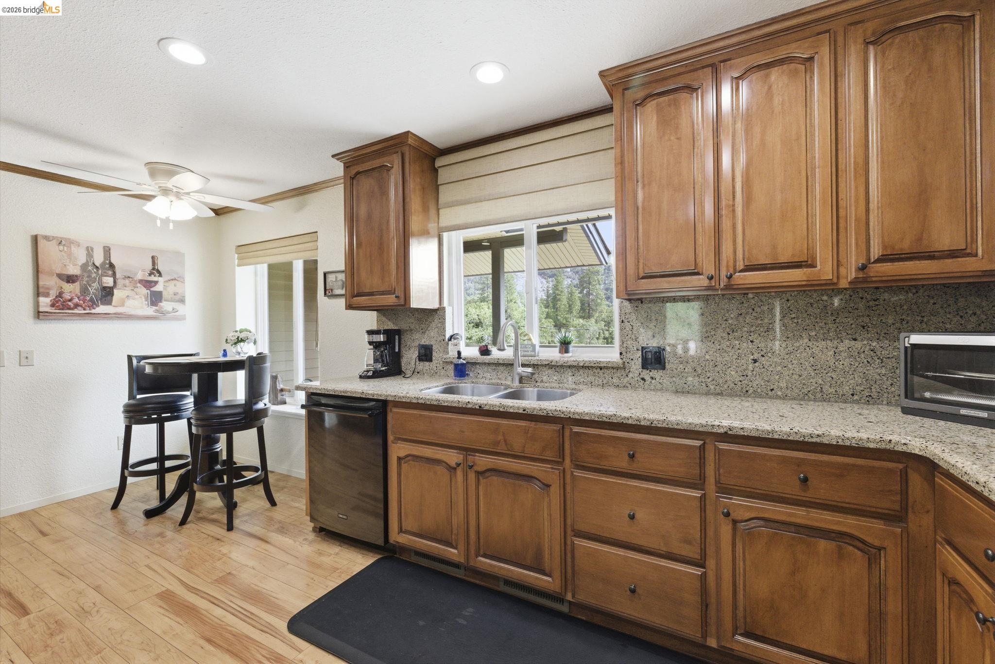 21955 Fallview Drive Sonora, CA 95370 - Photo 10 of 32 a kitchen with stainless steel appliances granite countertop a refrigerator a sink dishwasher a dining table and chairs with wooden floor