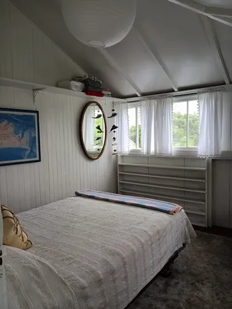 a bedroom with a bed and a lamp on dresser next to a window