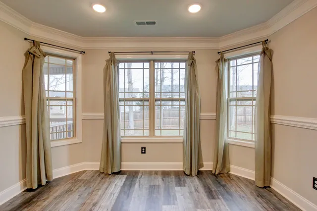 a view of an empty room with window and wooden floor