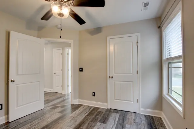 a view of an empty room with wooden floor and a window