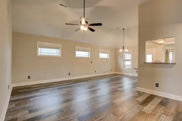 an empty room with wooden floor cabinet and windows