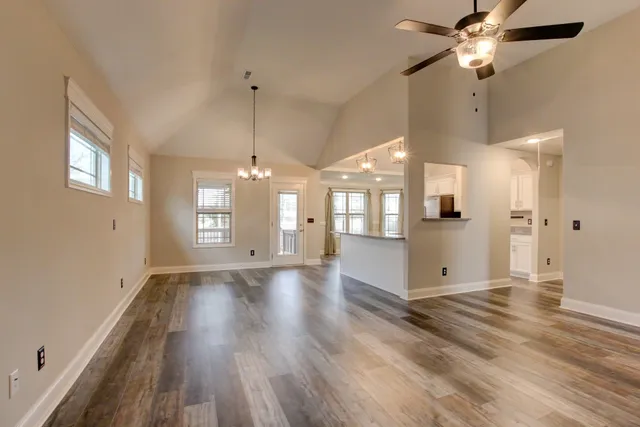 a view of an empty room with window and chandelier fan