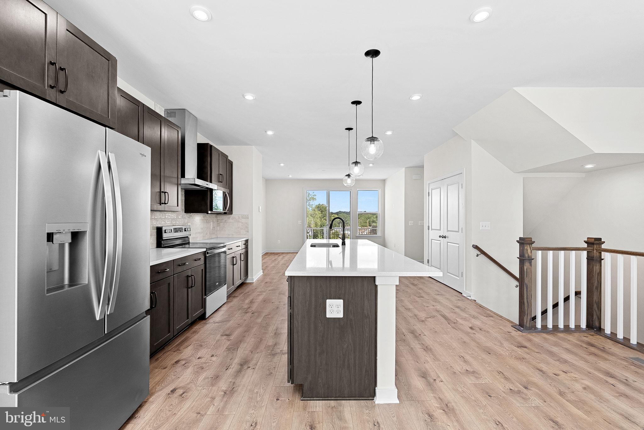 a large kitchen with stainless steel appliances kitchen island granite countertop a refrigerator and a stove top oven