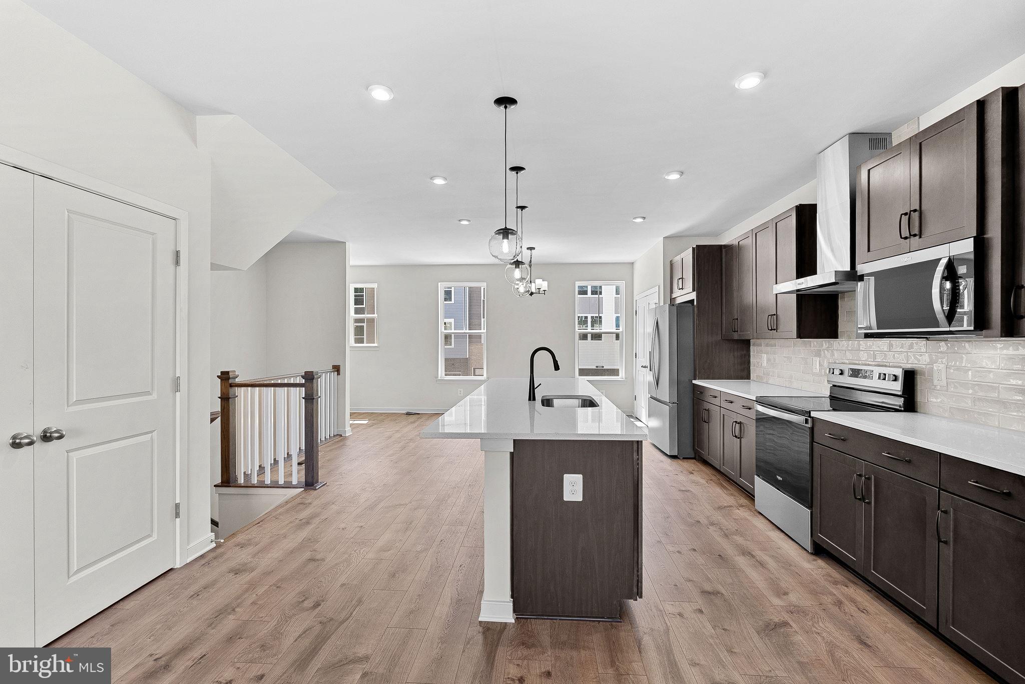 4151 Mountjoy Way Dumfries, VA 22026 - Photo 15 of 41 a large kitchen with stainless steel appliances kitchen island granite countertop a stove a sink dishwasher and a refrigerator with wooden floor
