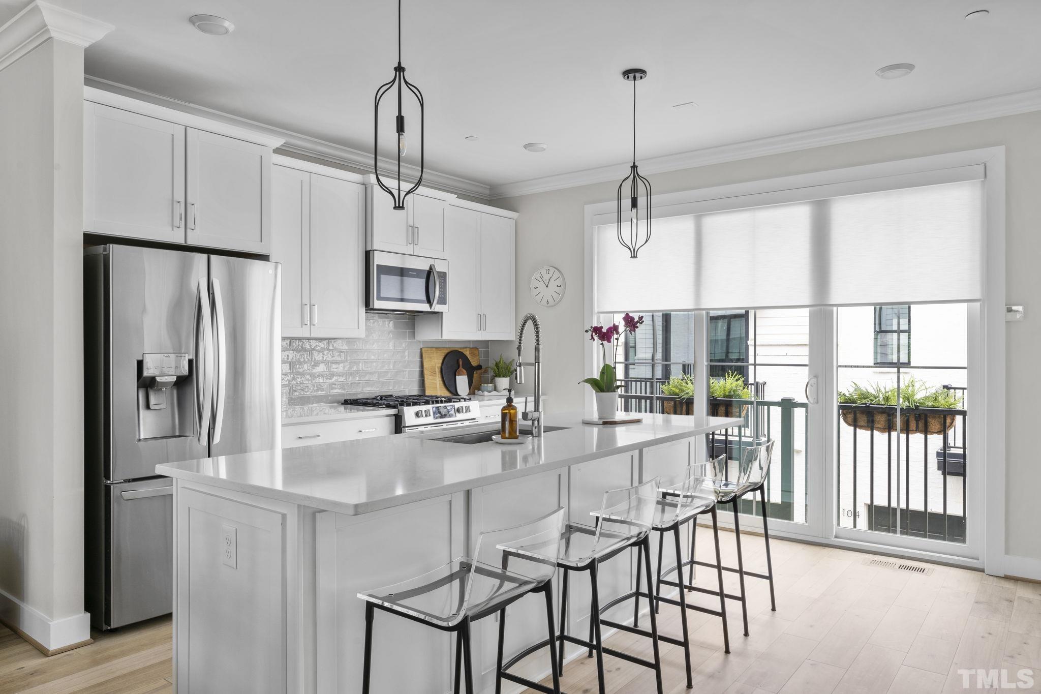1610 Draper View Loop, Unit 104 Raleigh, NC 27608 - Photo 11 of 41 a kitchen with kitchen island granite countertop a center island a refrigerator cabinets and a dining table