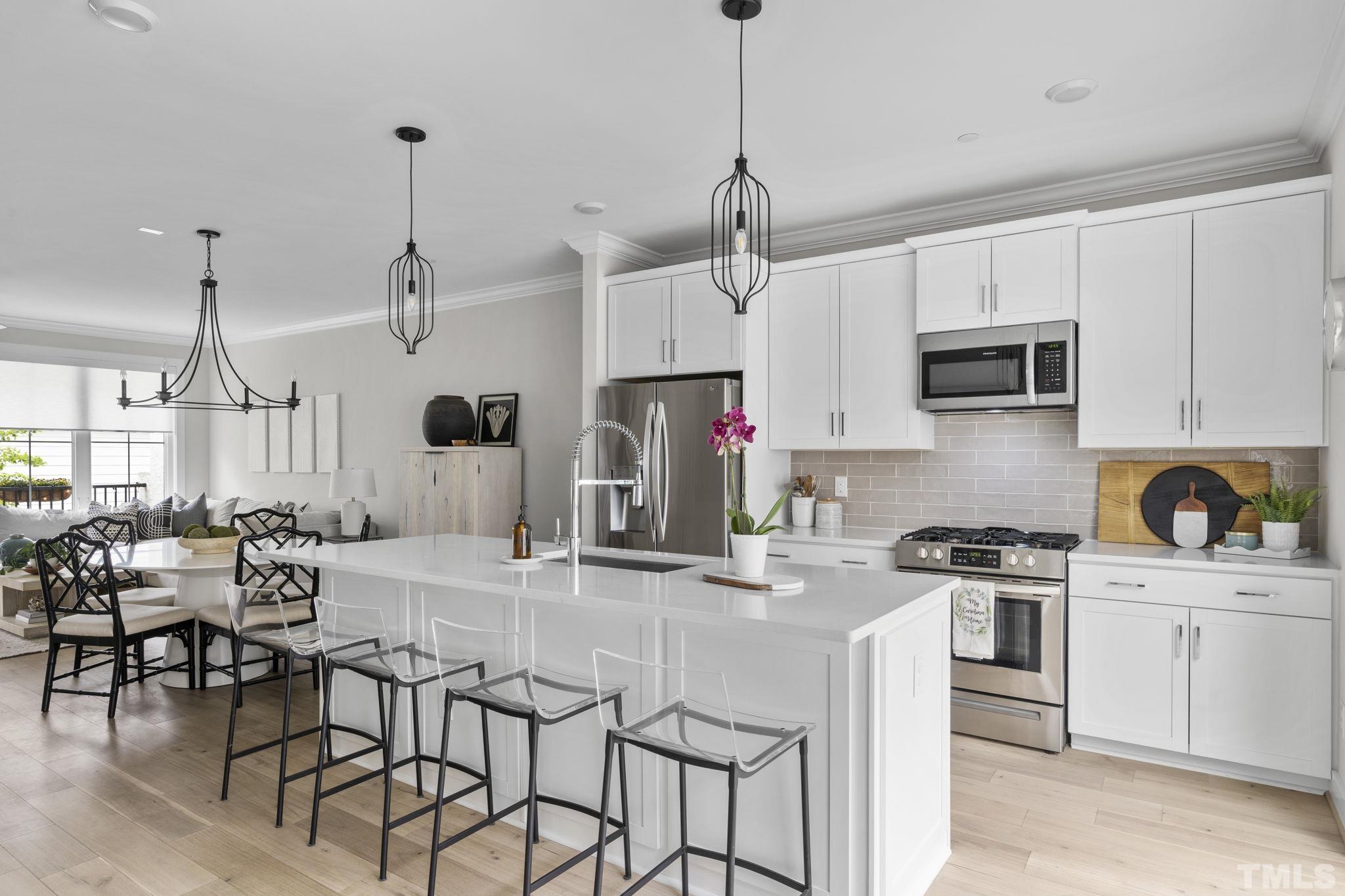 1610 Draper View Loop, Unit 104 Raleigh, NC 27608 - Photo 12 of 41 a kitchen with stainless steel appliances granite countertop a stove top oven a refrigerator a sink a dining table and chairs