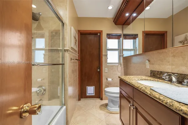 a bathroom with a granite countertop sink a toilet a mirror and shower