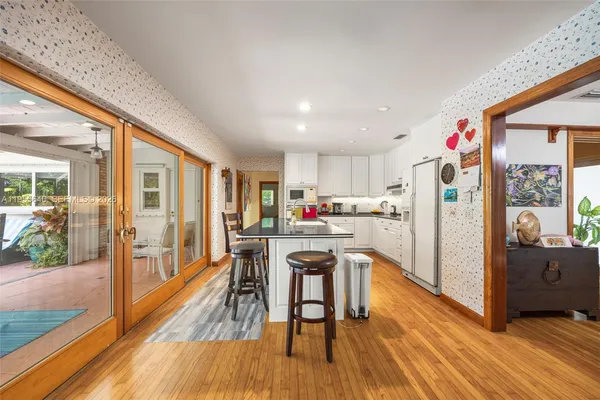a kitchen with stainless steel appliances granite countertop a refrigerator a stove top oven and a dining table with wooden floor