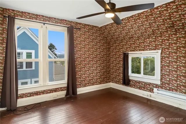 a view of an empty room with wooden floor and a window