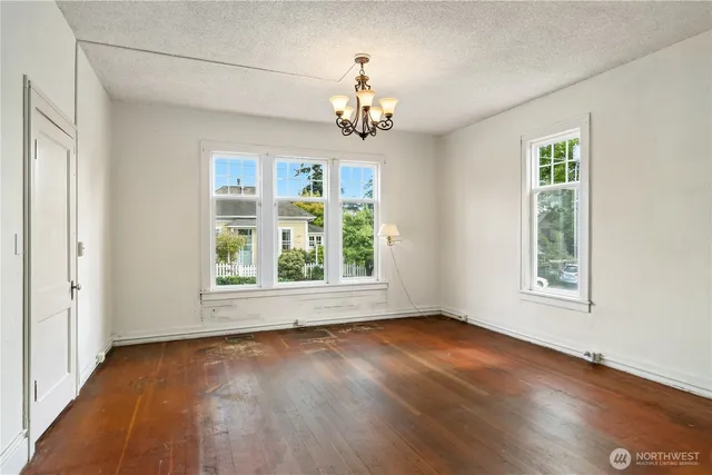 an empty room with wooden floor chandelier and windows