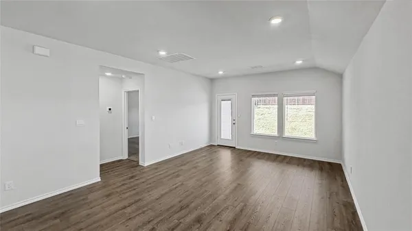 an empty room with wooden floor and windows