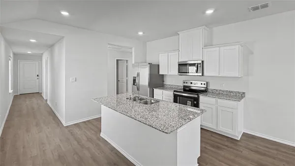 a kitchen with stainless steel appliances granite countertop a refrigerator a stove top oven a sink and dishwasher