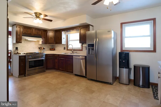 a kitchen with stainless steel appliances granite countertop a sink a stove a refrigerator cabinets and a window