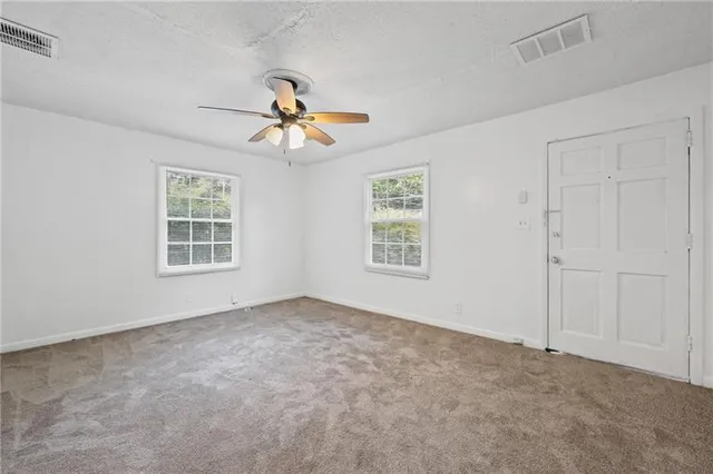 an empty room with windows and fan