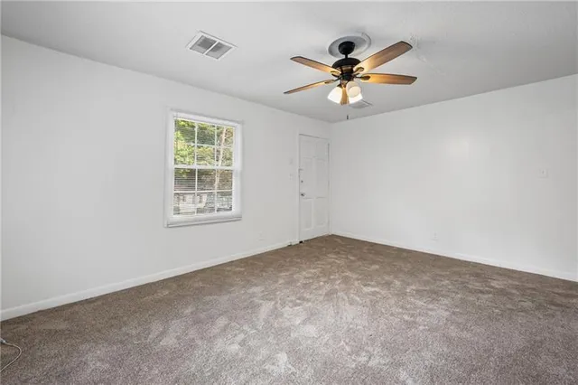 an empty room with chandelier fan and windows