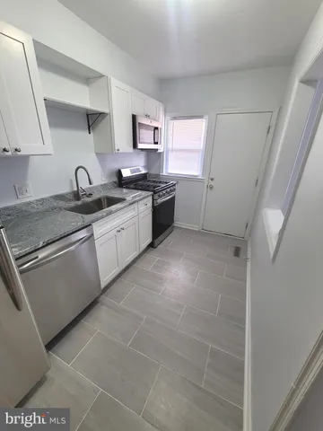 a large kitchen with stainless steel appliances granite countertop a sink and cabinets