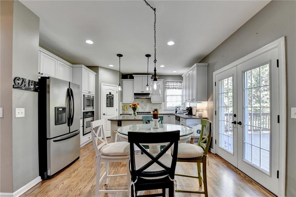 1973 Hamilton Mill Parkway Dacula, GA 30019 - Photo 29 of 105 a kitchen with stainless steel appliances a dining table chairs refrigerator and wooden cabinets