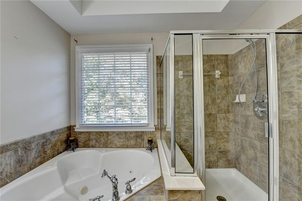1973 Hamilton Mill Parkway Dacula, GA 30019 - Photo 54 of 105 a bathroom with a bathtub and a shower