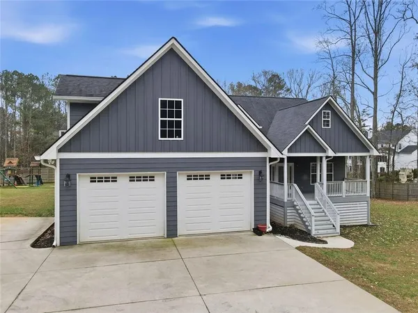 a view of house with wooden fence next to a yard