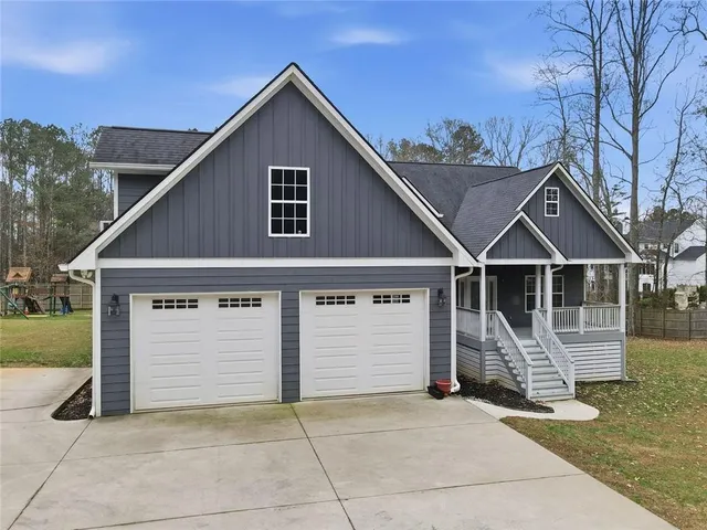 a view of house with wooden fence next to a yard