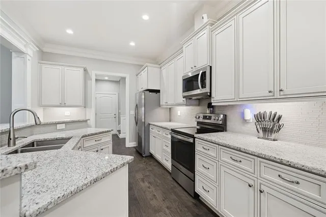 a kitchen with stainless steel appliances granite countertop a sink stove refrigerator and cabinets