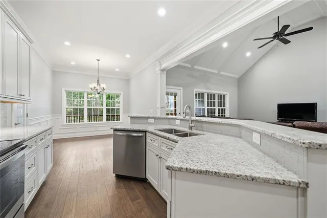 a large kitchen with granite countertop a sink and dishwasher with wooden floor