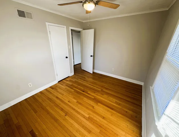 a view of a room with wooden floor and a ceiling fan
