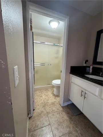 a spacious bathroom with a granite countertop sink a toilet and a mirror